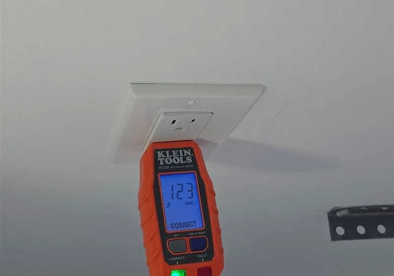 Electrician testing an outlet with a voltage tester during a safety inspection