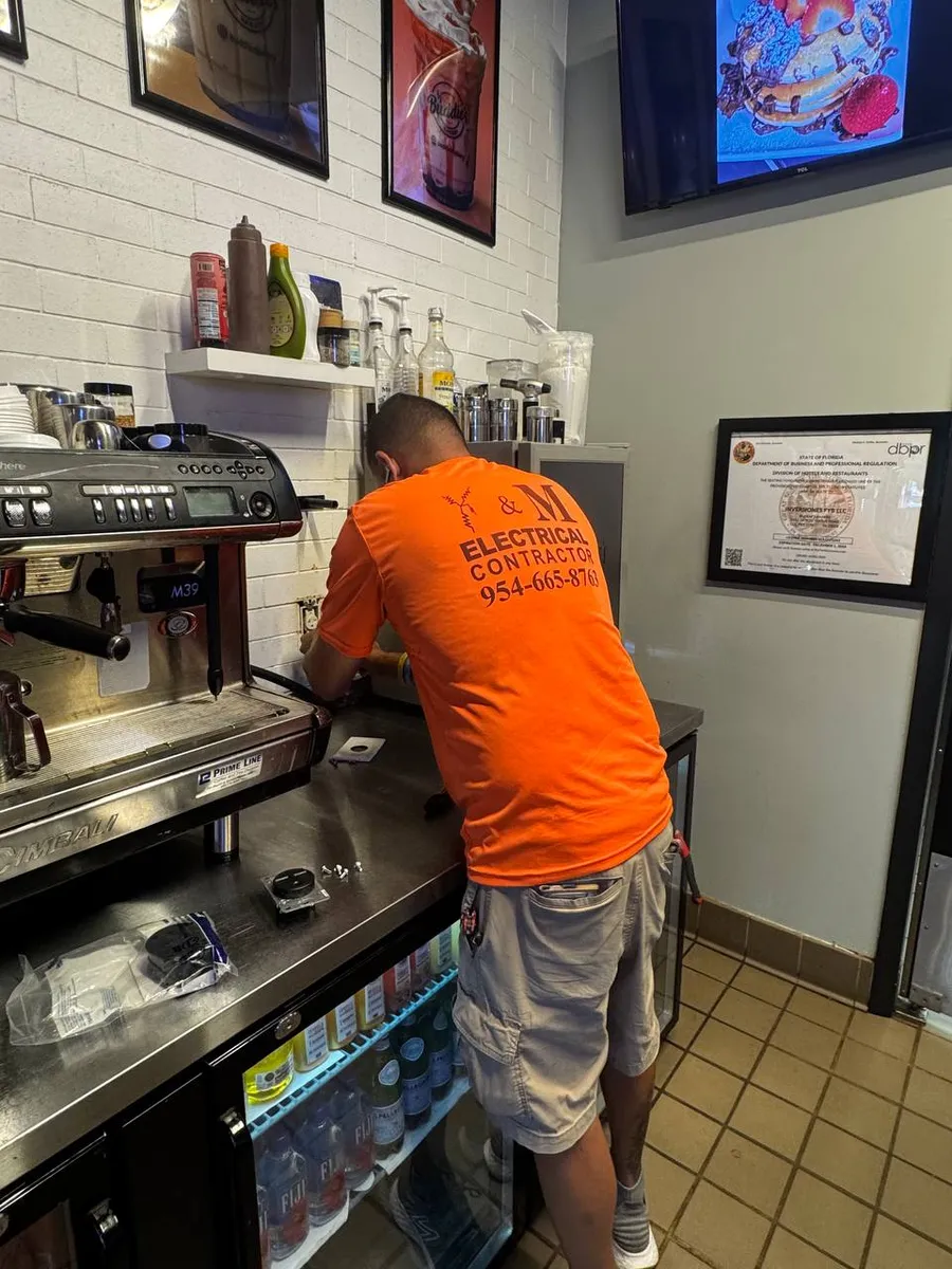Electrician working behind the espresso bar of a coffee shop