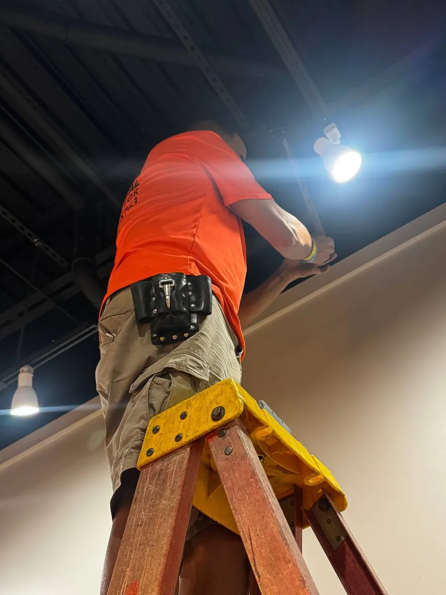 Y&M electrician on a ladder installing a light fixture
