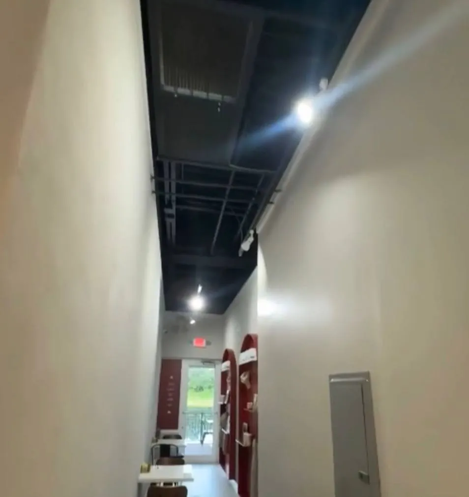 Office hallway with track lighting, exit sign and electrical panel