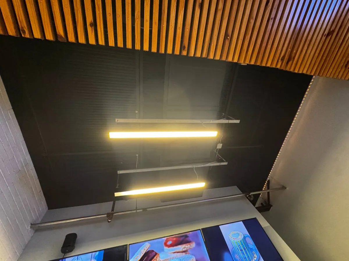 Linear pendant lights over a counter under a wood slat ceiling
