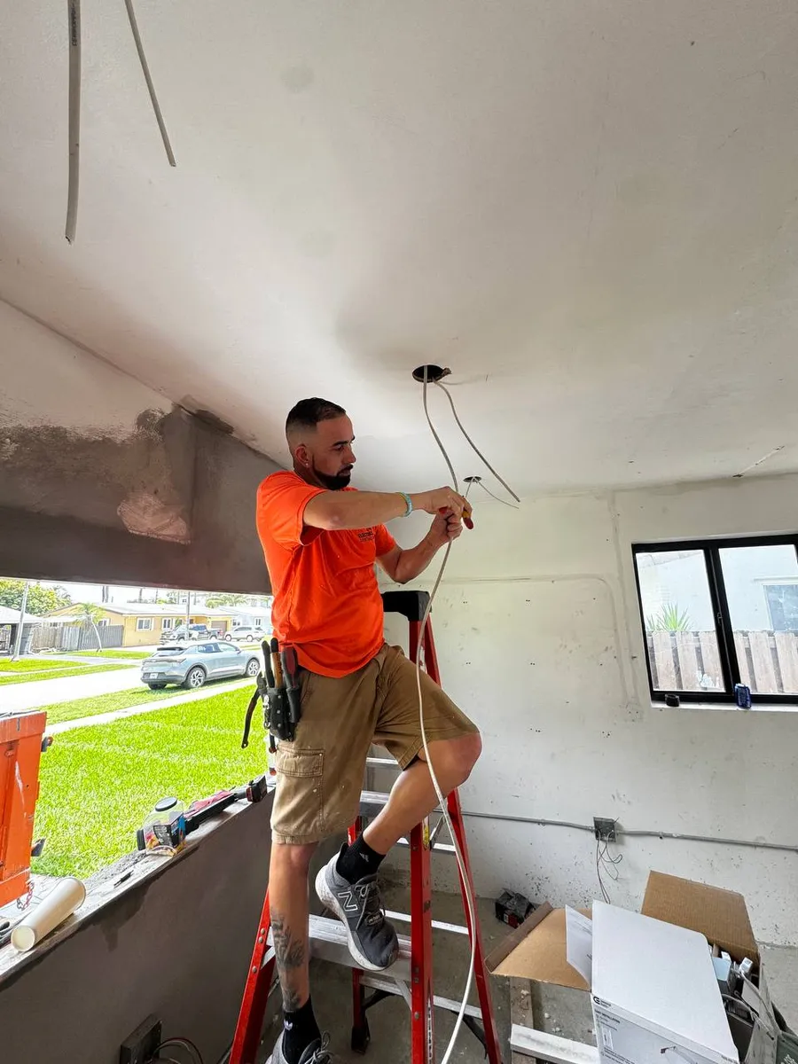 Electrician on a ladder wiring a ceiling in a new construction home