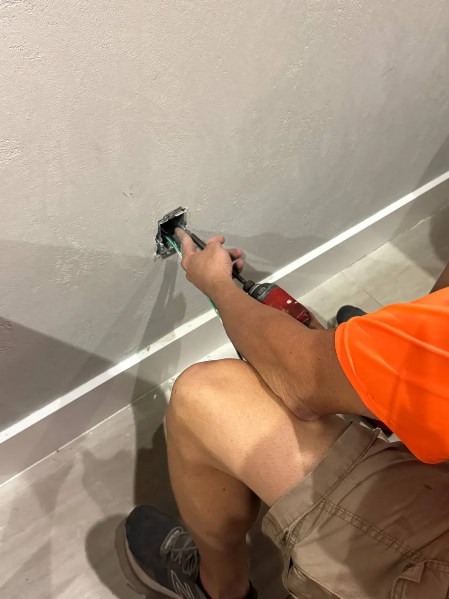 Electrician installing an outlet box in a finished wall