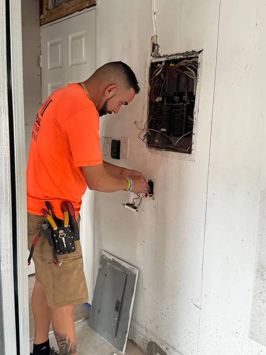 Electrician wiring outlets next to a new panel in a new build
