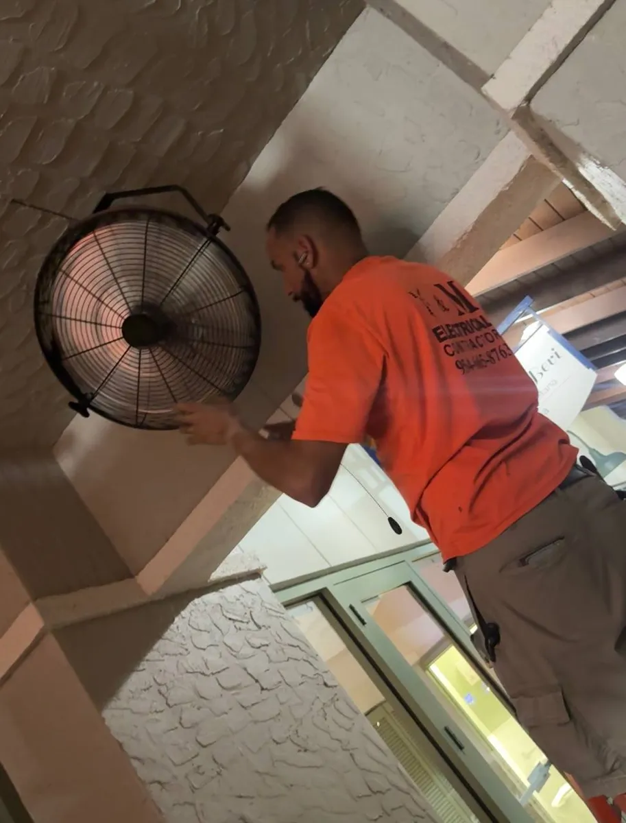 Y&M electrician mounting a wall fan on a restaurant patio
