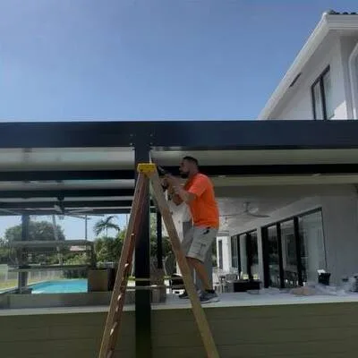 Electrician on a ladder wiring a pergola by the pool