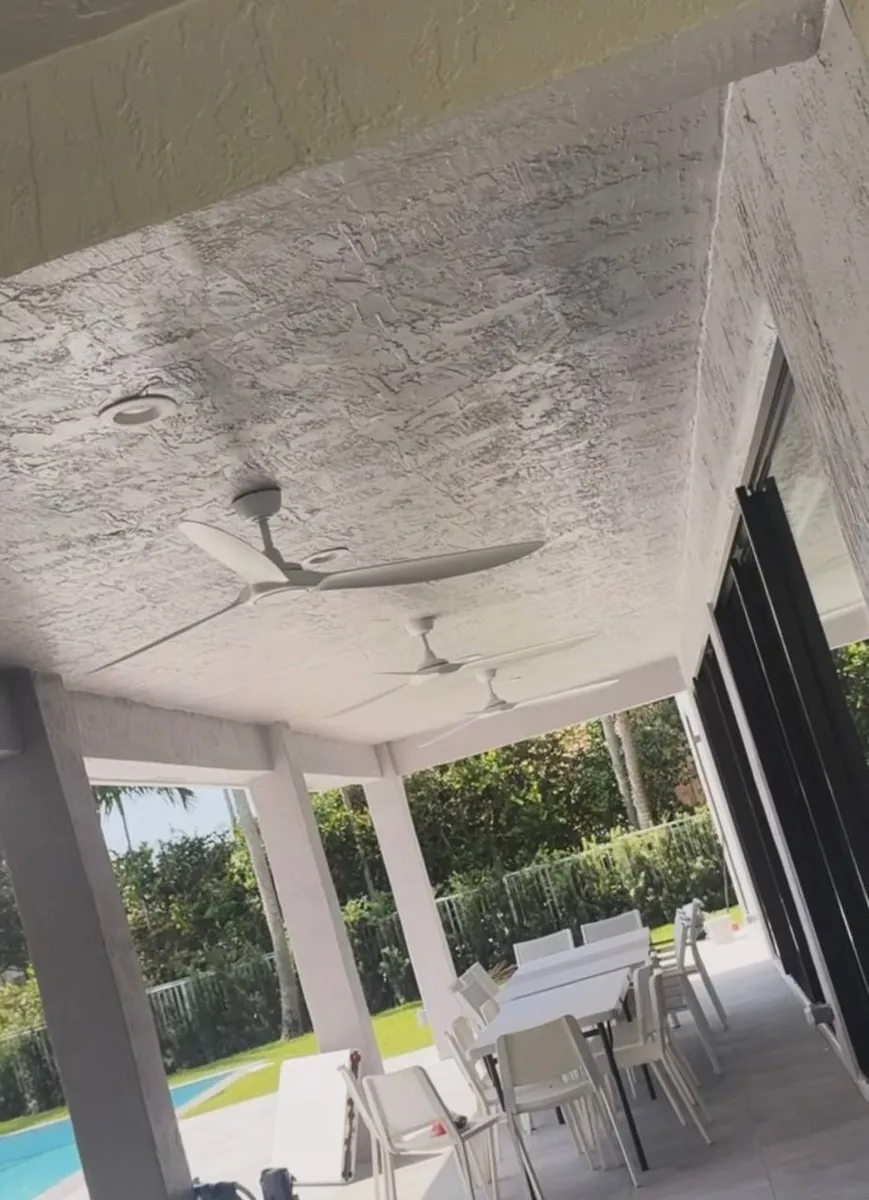 Two white outdoor ceiling fans and a recessed light on a poolside patio