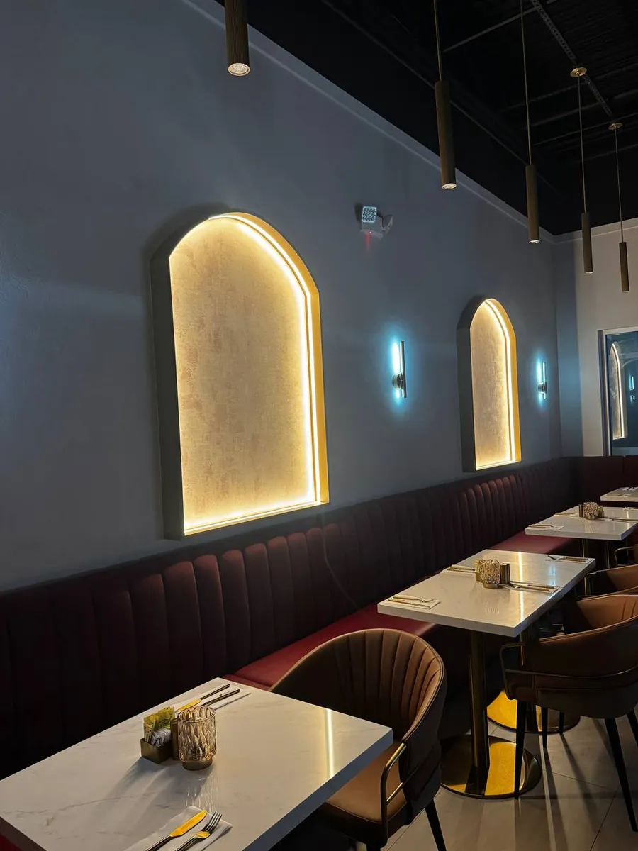 Restaurant dining room with backlit arches, pendant lights and wall sconces
