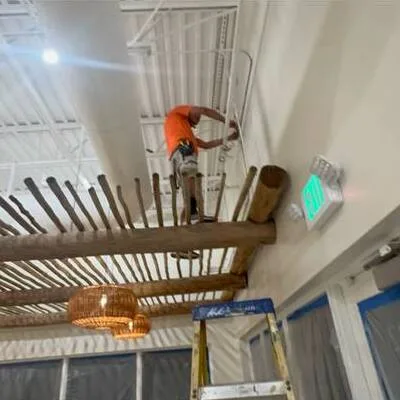 Electrician installing emergency exit sign and pendant lighting in a restaurant